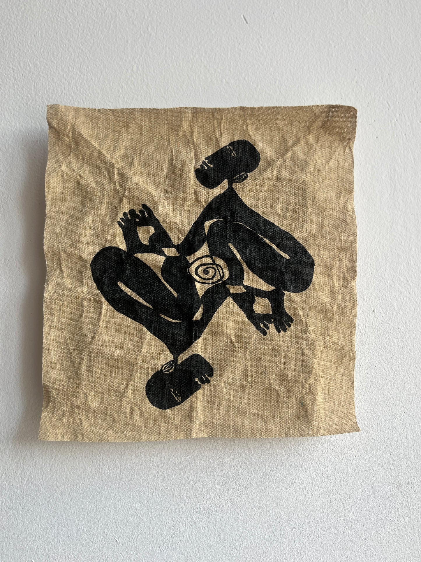 Textile with black silhouette of a person and a spiral on a beige background