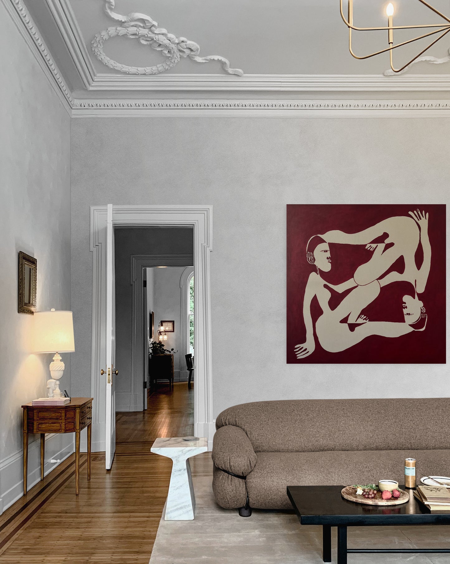 Living room with a modern sofa, coffee table, and wall art of two nude figures.