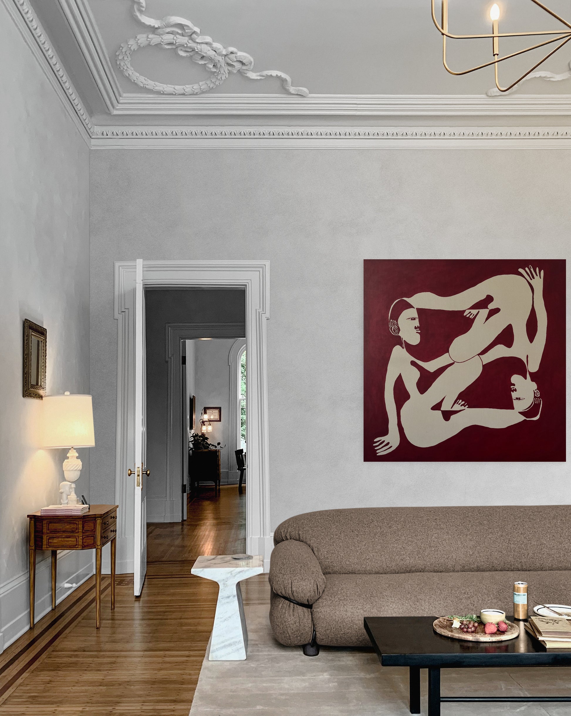 Living room with a modern sofa, coffee table, and wall art of two nude figures.