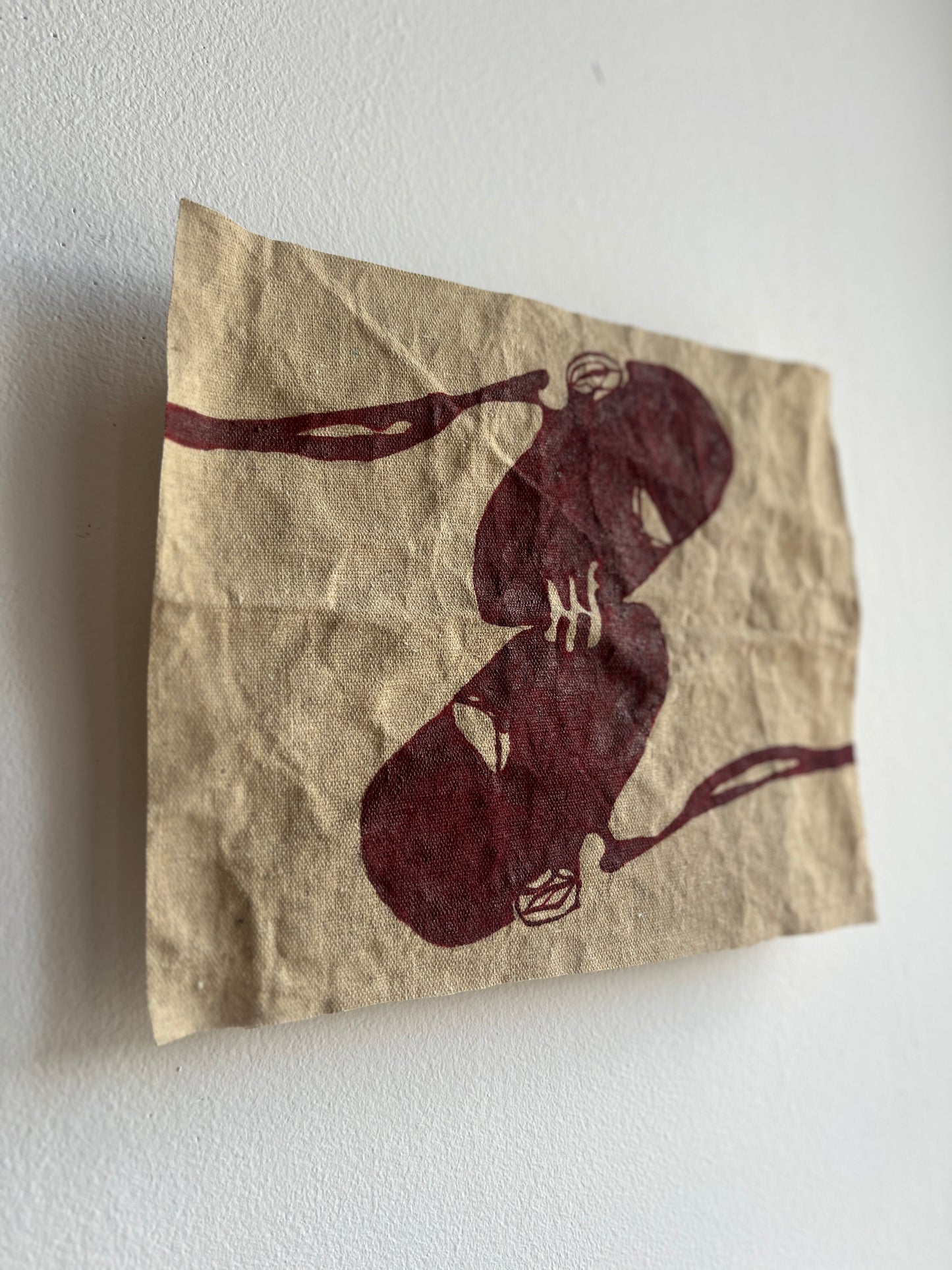 Raw canvas with two abstract figures kissing on a white wall.