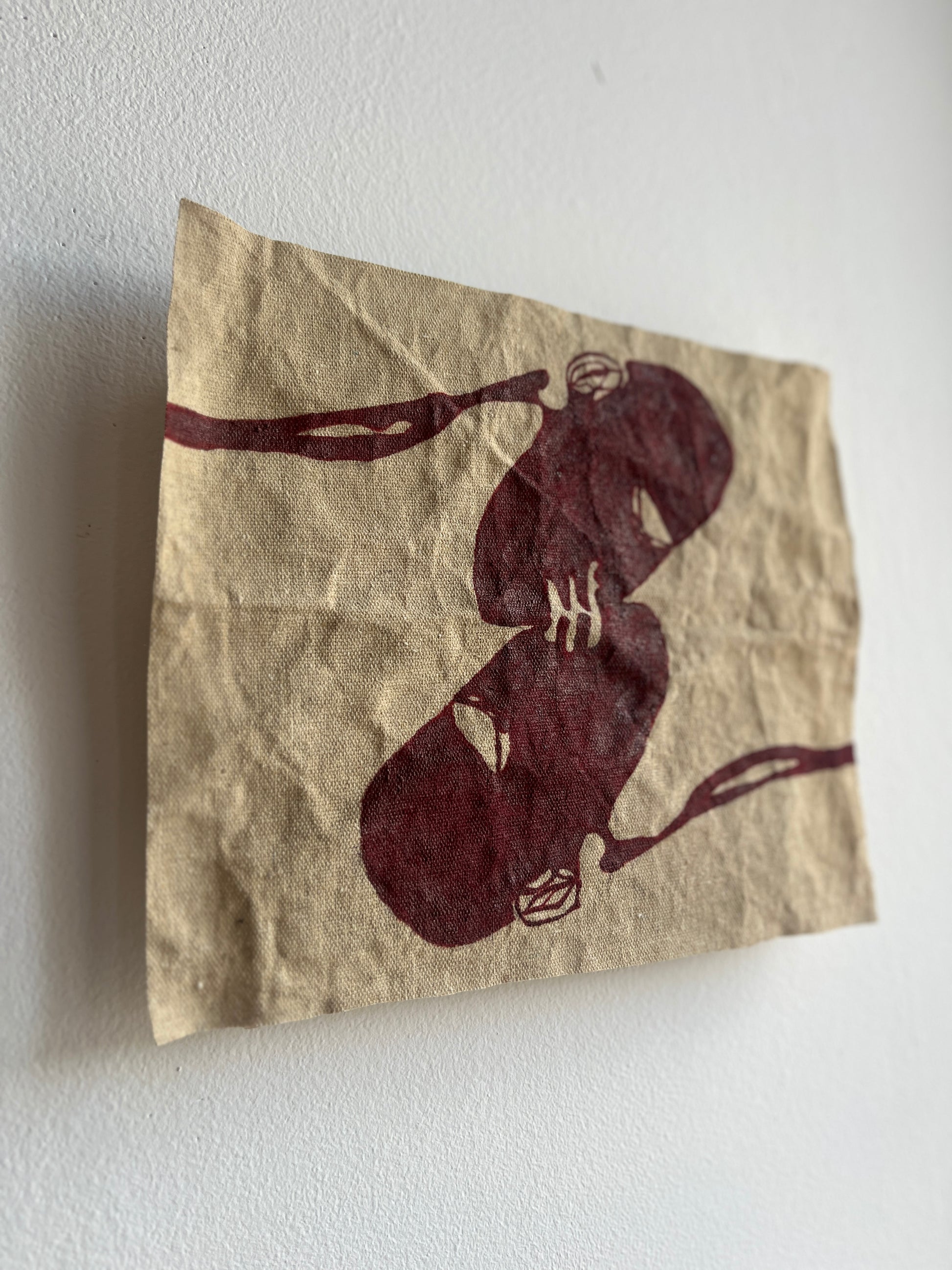 Raw canvas with two abstract figures kissing on a white wall.