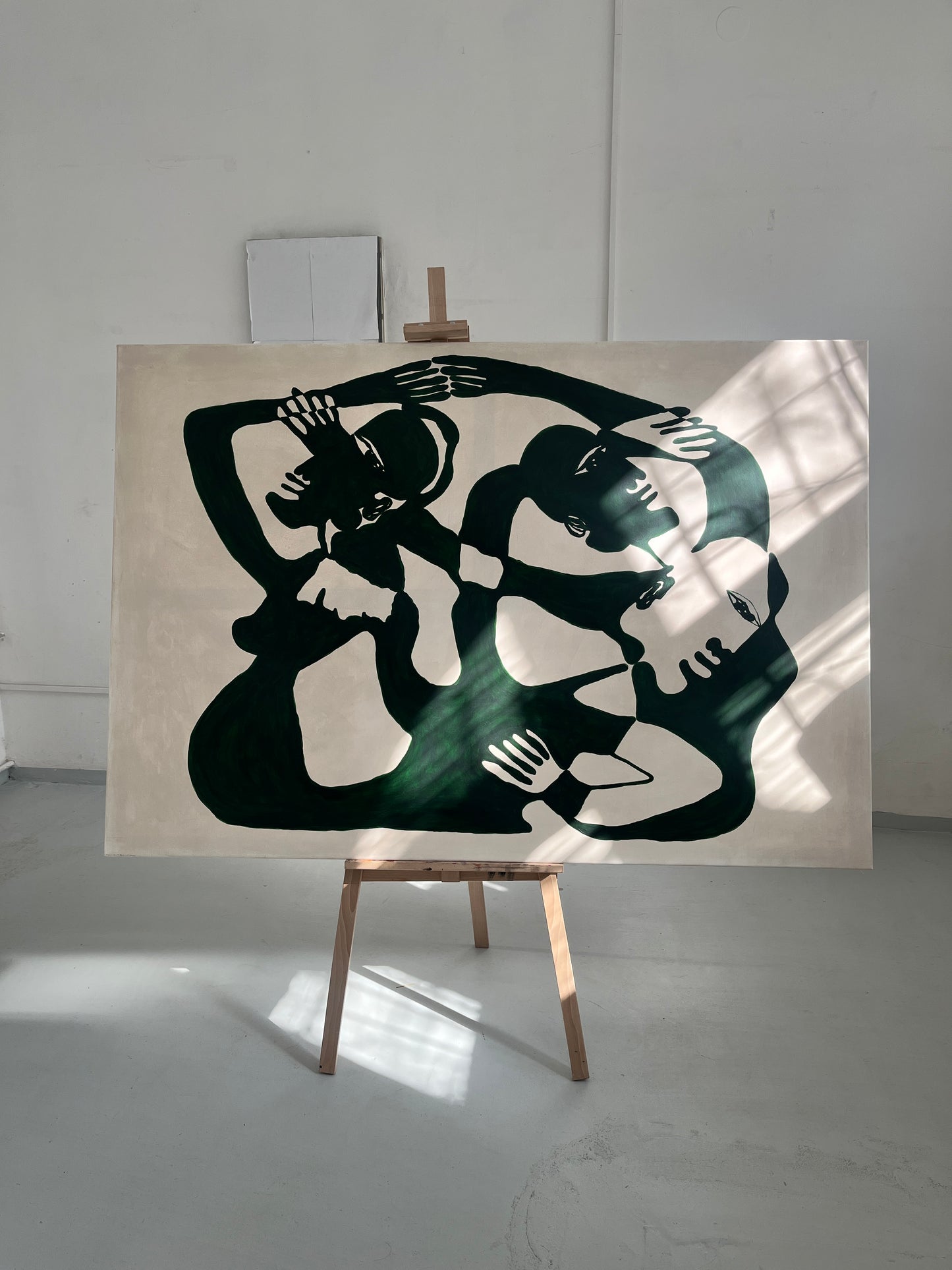 Abstract green and white artwork on an easel in a naturally lit gallery