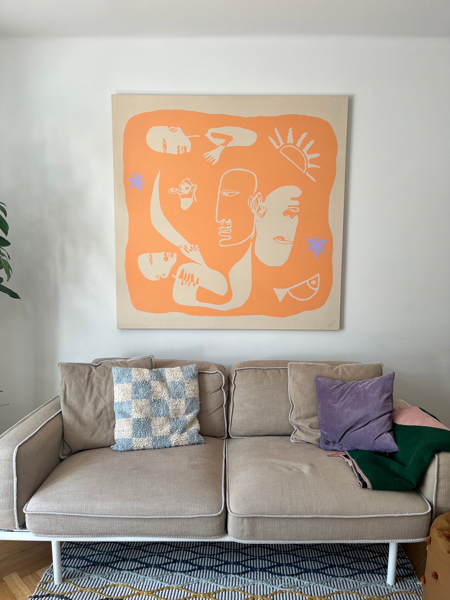 Gray sofa with colorful cushions in a room with abstract wall art.